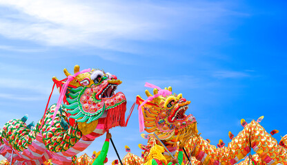 Two colorful Chinese dragon dance performances against blue sky background during Chinese New Year...