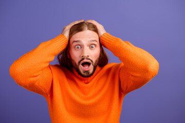 Photo of young man wearing bright orange jumper surprised touching head unbelievable wtf reaction...