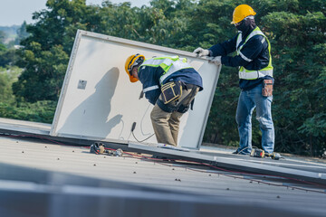 Fototapeta premium Worker Technicians are working to construct solar panels system on roof. Installing solar photovoltaic panel system. Men technicians carrying photovoltaic solar modules on roof.