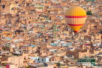 Fototapeta premium Hot air balloon flying over many buildings within the Medina of Fes, Morocco