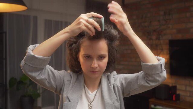 A woman explains and shows how to properly style her hair at home and wind bangs on curlers at an online training for hairstylists. The concept of hair care, fashion and beauty.