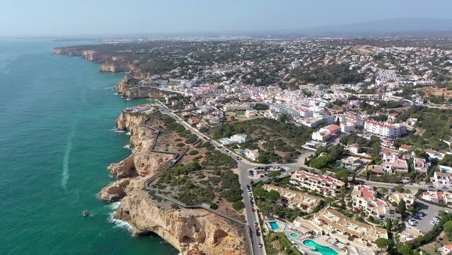Carvoeiro, Portugal. Aerial perspective of this coastal city. Turist boats visiting the famous cave from this region. Famous travel destination. Golden beaches and turqoise water. Drone ascending.