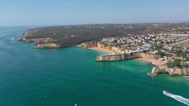 Aerial perspective of Algarve coastline. View of Armacao de Pera. Luxury hotels and urbanisation. Gloden beaches, turquoise water. High cliffs. Famous travel destination. Drone panning right