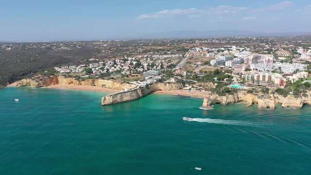 Aerial perspective of Algarve coastline. View of Armacao de Pera. Luxury hotels and urbanisation. Gloden beaches, turquoise water. High cliff. Famous travel destination. Turist boat visiting the caves