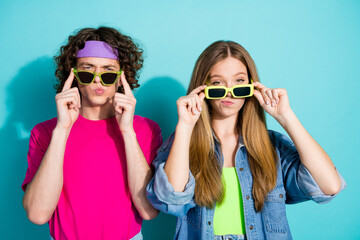 Photo of two teen friends in second hand shop touching their green sunglasses with suspicious...