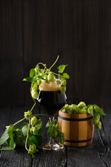 Hops and a glass of beer on a wooden background