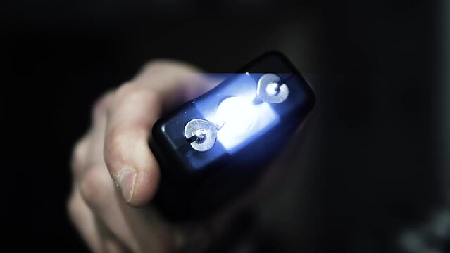 Stun gun in a man's hand, electric discharge, portable shocker, dog repeller. Slow motion camera.