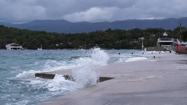 Powerful waves crashing the coast in the harbour of Njivice, Croatia after Storm Ciar&aacute;n smashed into Krk Island. Disquiet sea surface, huge water splashes, boats and yachts rocking in the background.