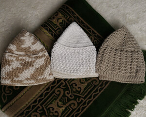 Collection of songkok hats, decorative Islamic headdresses worn by Muslim men, isolated on white fur carpet background from different angles. Songkok is made from hand-knotted thread ramadhan eid fitr
