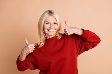 Photo of funky confident woman wear red sweater showing two thumbs up isolated beige color...