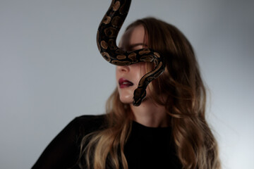 young blond woman with black dress and real snake python 