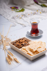 Tarhana chips, Turkish snack made with flour, wheat berries, mint, yogurt and spices also known as frik with pistachio, walnut and almonds and a traditional fabric in the background