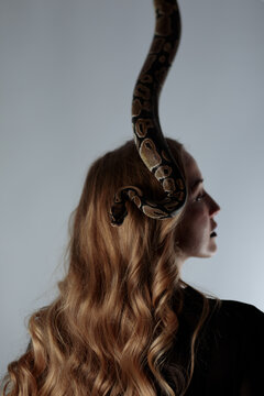 young blond woman with black dress and real snake python 