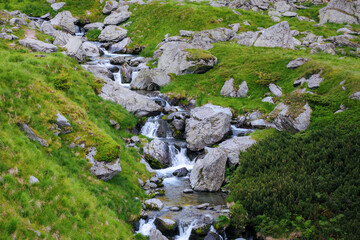Fototapeta na wymiar rapid balea water stream among stones and boulders on the hills of fagaras ridge. beautiful scenery in romanian mountains. view from above