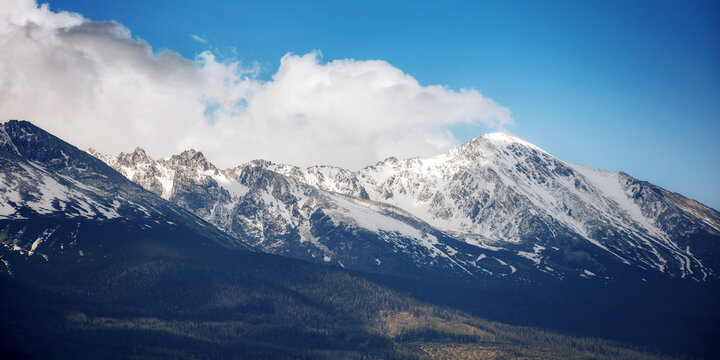 nature background of mighty high tatra ridge in spring at high noon. snow capped rocky peaks of slovakia beneath a cloudy sky