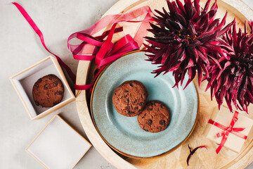 Chocolate chip cookies on a wooden tray with dahlias.