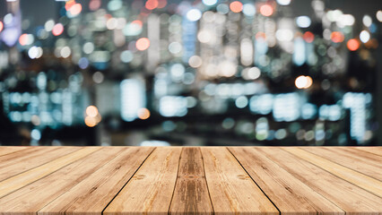 Empty wooden table top with lights bokeh on blur city background.