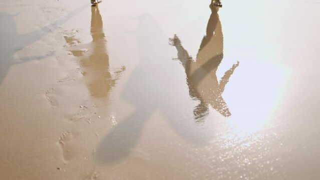 Reflections, shadows of people with surfboards on clear sand. Surfers couple barefoot feet walk on wet sandy beach by sea surf. Low angle. Footprints of man, woman go surfing to lineup in ocean water