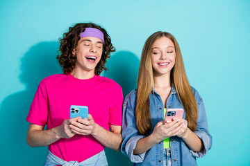 Photo of youth funky couple teenagers holding smartphones reading dialogues each other spying...