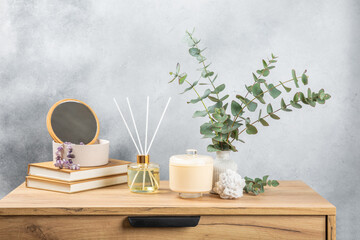 Green eucalyptus leaves in a vase stand on a chest of drawers against the background of a wall. Aromatherapy.Beautiful eucalyptus bouquet.Minimalist interior with flowers, candles and aroma diffuser.