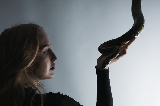 python snake plays with a young blond woman