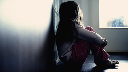 Sad child suffering from depression sitting alone in corridor feeling loneliness. Scared fearful small girl covering face in silhouette at home. Childhood anxiety