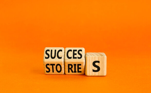 Success stories symbol. Turned wooden cubes and changed the word stories to success. Beautiful orange table, orange background, copy space. Business success stories story concept.