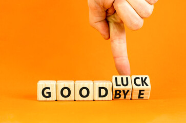 Good luck or goodbye symbol. Concept words Good luck or Goodbye on beautiful wooden blocks. Beautiful orange background. Businessman hand. Business, motivational good luck concept. Copy space.