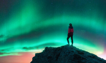 Northern lights and woman on mountain peak at night. Aurora