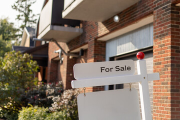 For sale sign in front of condo house in a residential neighborhood.