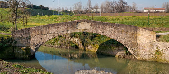 Fototapeta na wymiar Antique pedestrian bridge, called Ponte della Bionda, on the Navile canal: historic waterway of Bologna. Emilia Romagna, Italy