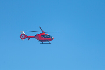 Fototapeta na wymiar Red coloured helicopter flying in the sky.