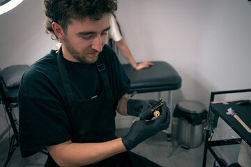 Male Tattoo Artist at Work in a Modern Tattoo Studio Preparing Equipment