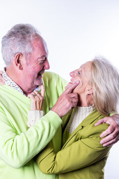 This heartwarming image captures a moment of playful affection between a senior man and woman. The man is seen teasingly pointing at the woman's nose, both sharing a moment of laughter and closeness