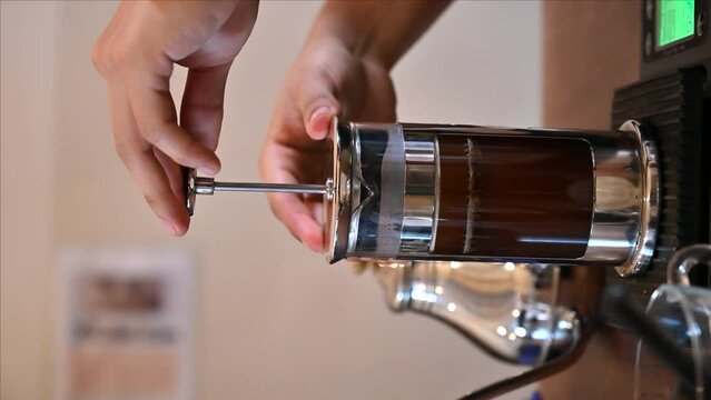 Making French press coffee. Pressing the plunger down. Vertical video