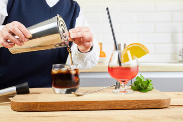Hobby and drinks concept. Female hand making cocktail drinks with citrus ingredient and bar tools...