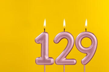 Candle 129 with flame - Birthday card on yellow luxury background