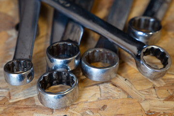 Various size chrome ring spanners on a wooden background 