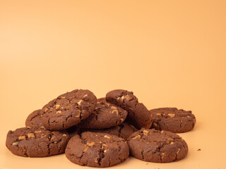 Chocolatey, rich cookies with contrasting white chocolate chips on an orange background. Cookies with white chocolate close-up.