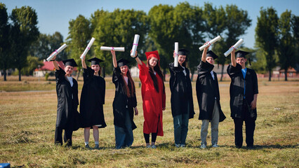 group of multiracial graduates holding diploma.