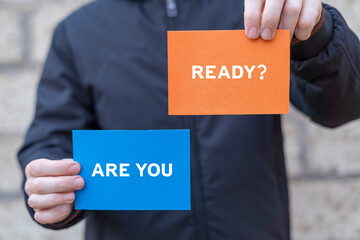 Business and Are you ready concept. Man holding paper cards with text: ARE YOU READY?