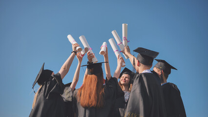 College graduates with caps tie their diplomas together.