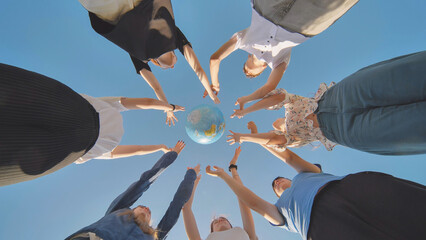 Friends hold and toss a geographic globe in their hands. The concept of keeping the world safe.