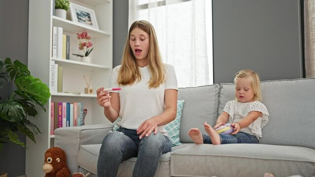 Surprised caucasian mother and daughter relaxing at home, shocked by fever measurement on thermometer