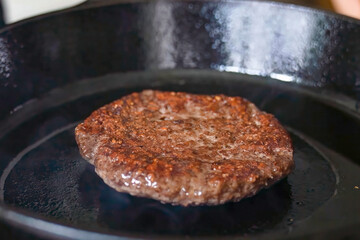 Cooking burger beef patty on a hot frying pan close up. Preparing burger, homemade. Grocery product advertising, menu.