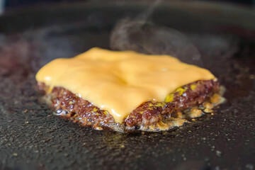 Cooking burger beef patty on a hot frying pan close up. Preparing burger, homemade. Grocery product advertising, menu.