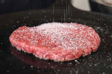 Cooking burger beef patty on a hot frying pan close up. Preparing burger, homemade. Grocery product advertising, menu.