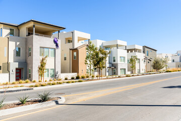 Row of new detached houses along a street in a housing development in California on a clear autumn...