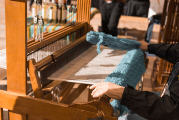 Master weaver is weaving the tapestry with diverse bright threads, close up. Artisanal at work