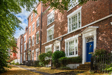 Row of renovated tradional British brick town houses with colourful wooden front doors in a city...